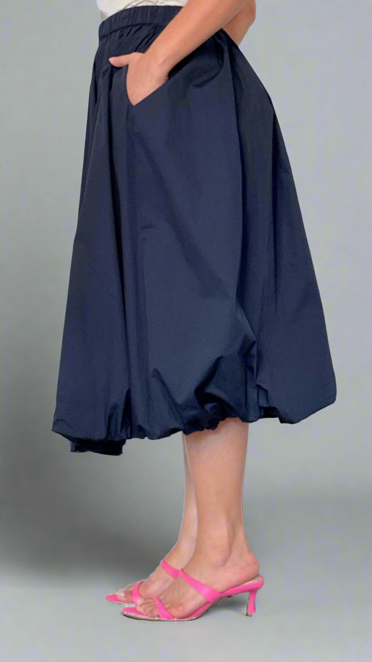 Person wearing a navy blue skirt with a white background